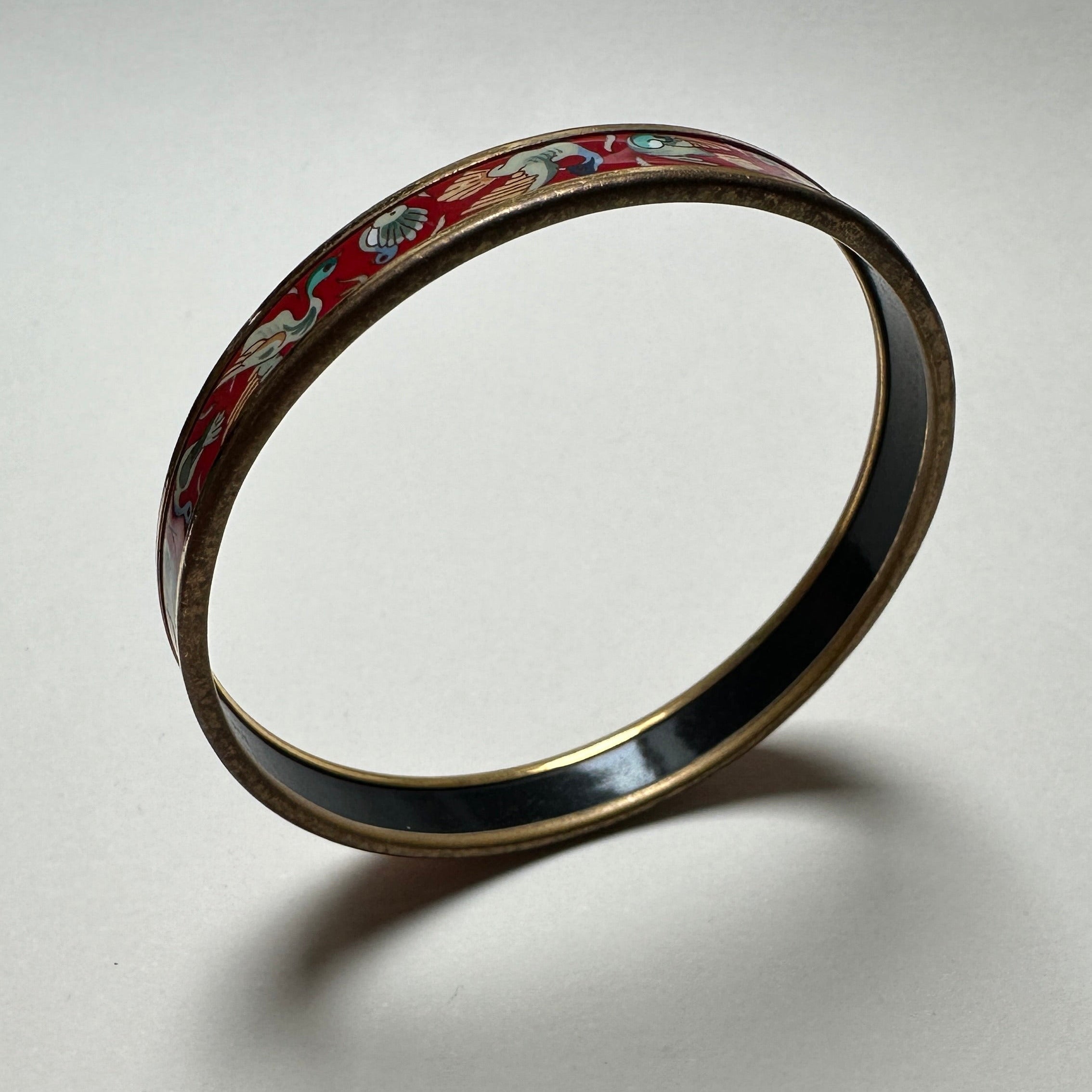 Détail artistique de l'émail Hermès : finesse du dessin "Oiseaux" aux teintes naturelles sur fond rouge profond.