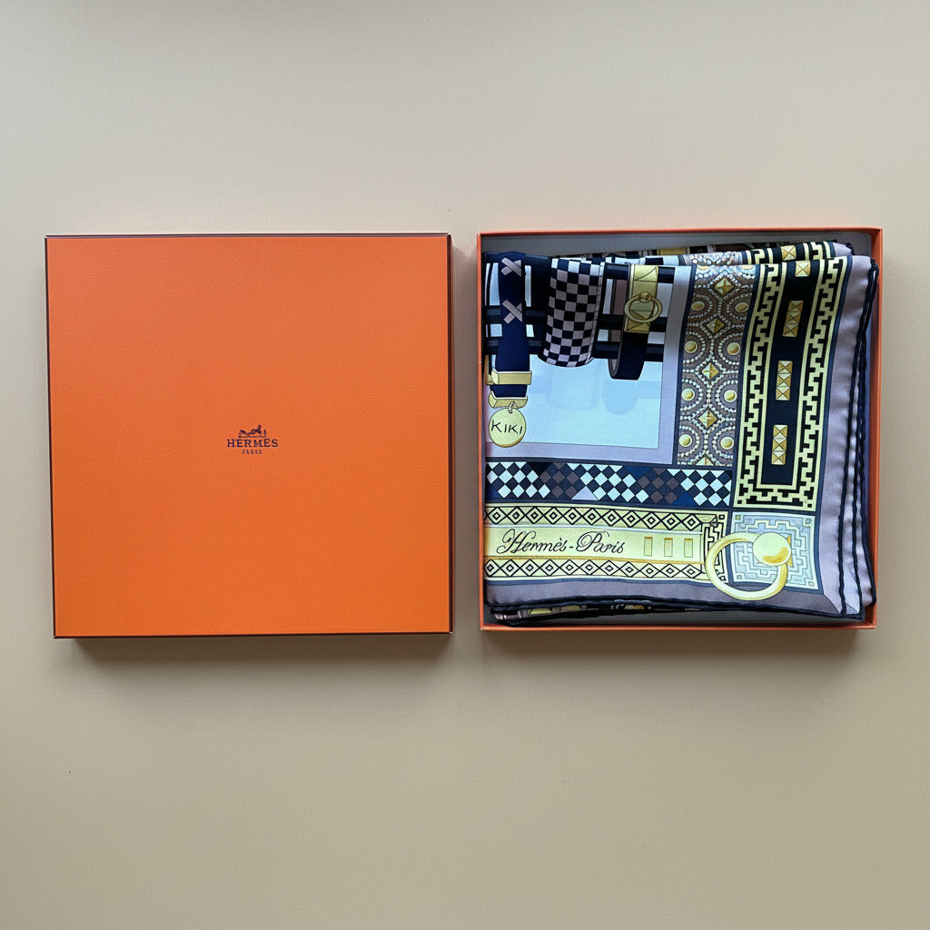 Carré Hermès Colliers de Chiens plié dans sa boîte orange d'origine.