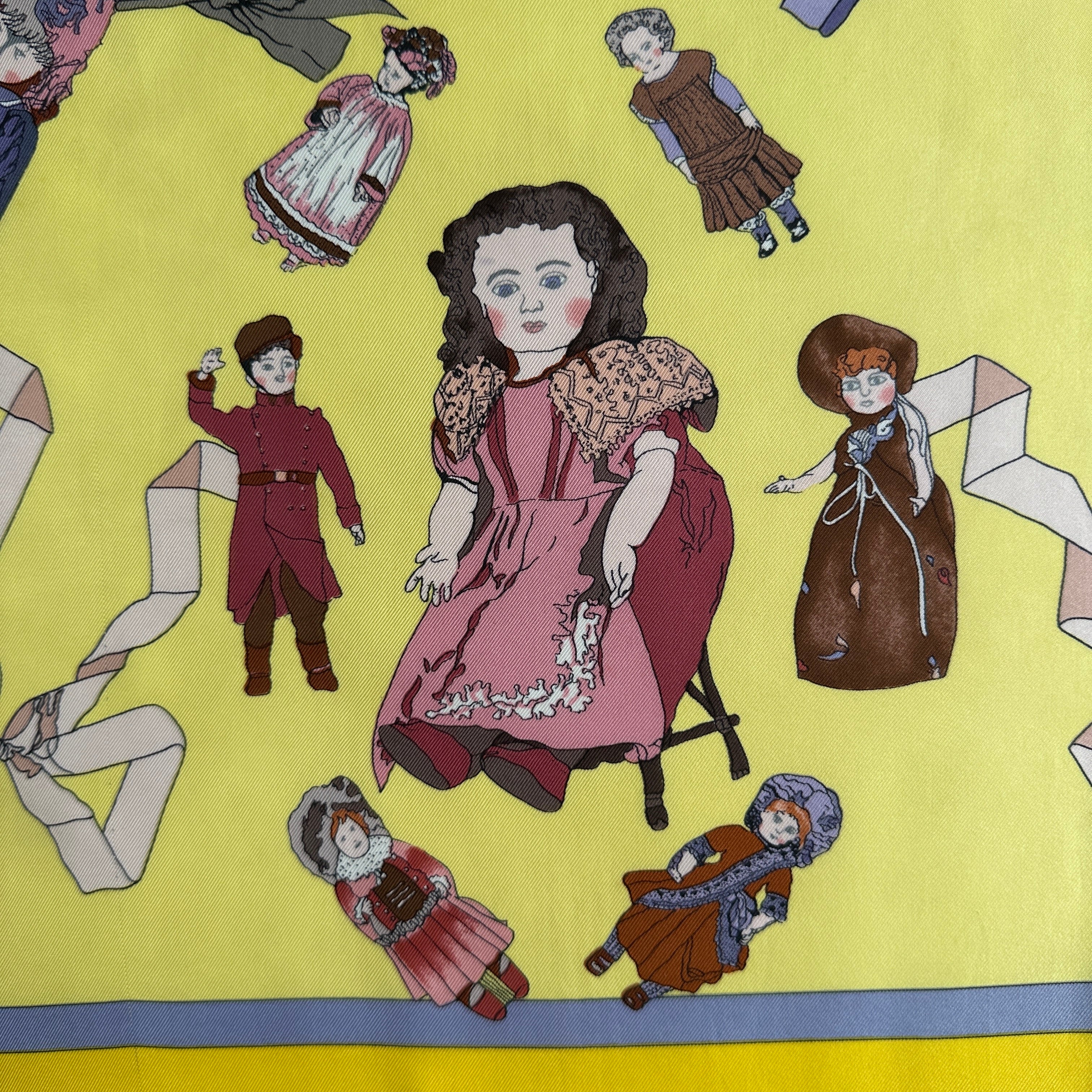 Détail d'une grande poupée brune au centre du foulard et d'un petit garçon en costume rouge.